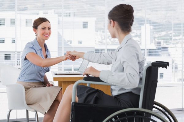 Businesswoman shaking hands with disabled colleague